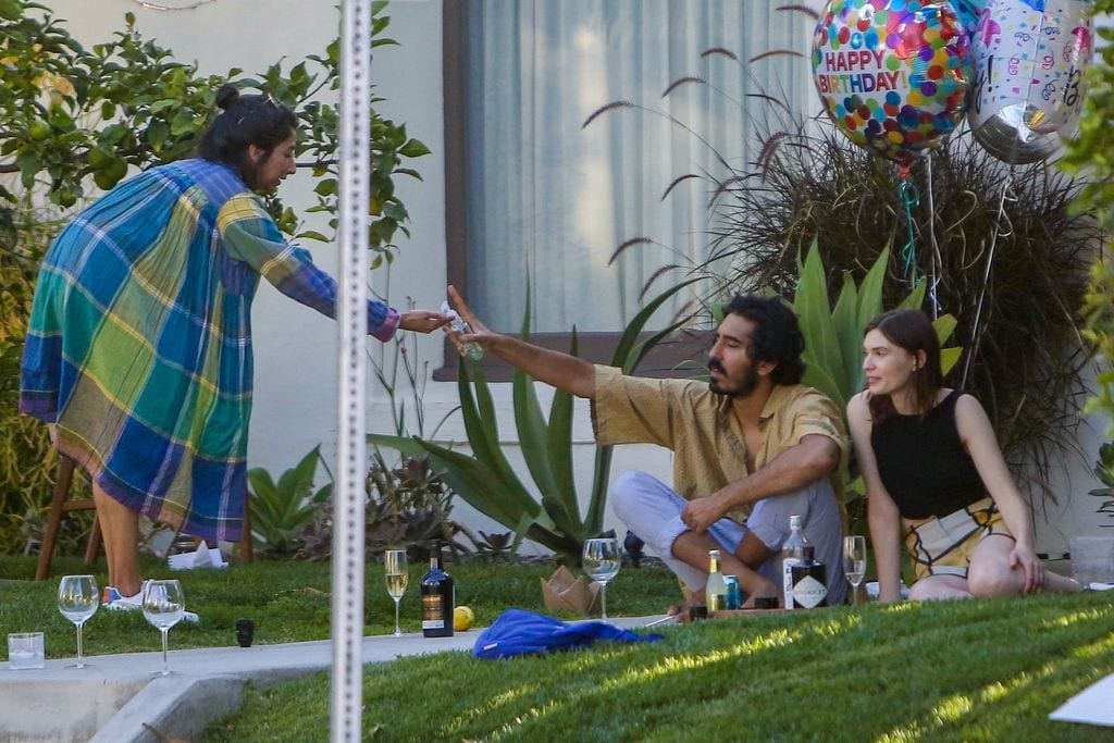 Dev Patel proporciona gel hidroalcohólico a una amiga en el jardín de su casa