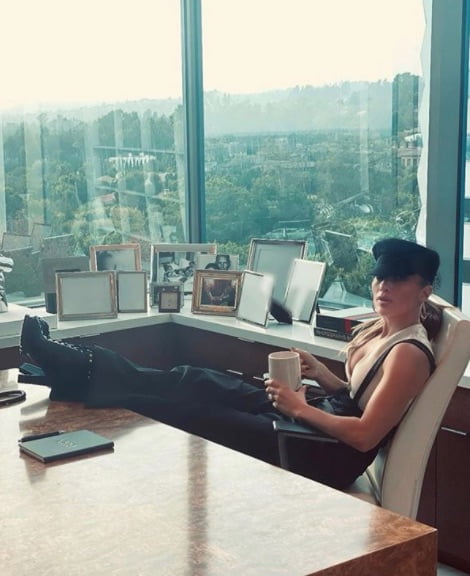 Sentada en un despacho de un rascacielos, con gorra, pantalón de tiro alto y botas de tacón