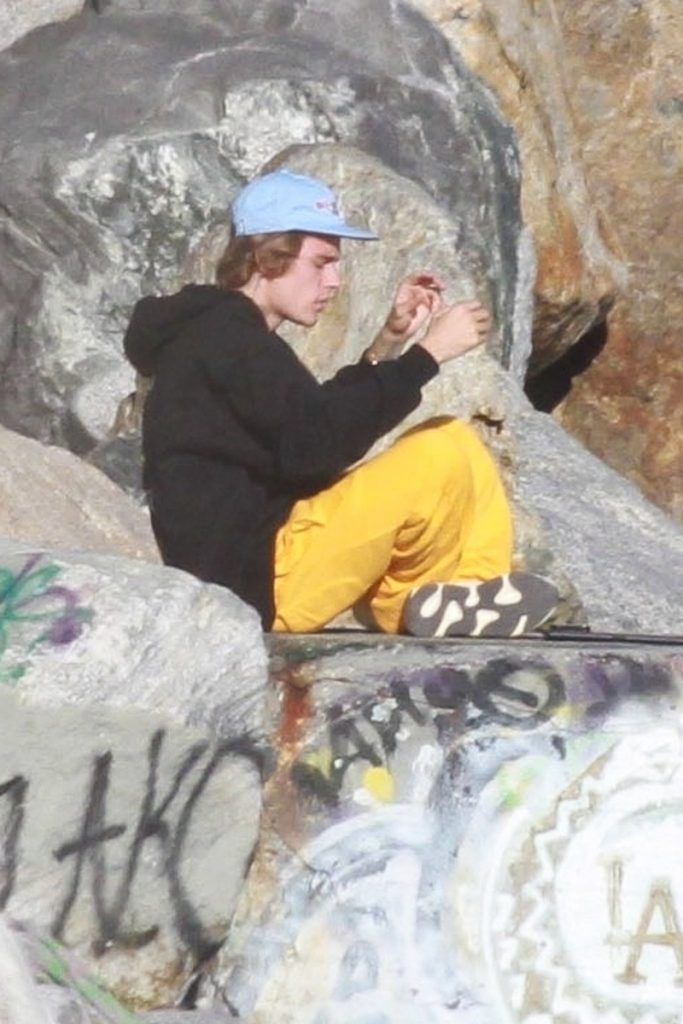 Justin Bieber sentado en una roca en la playa