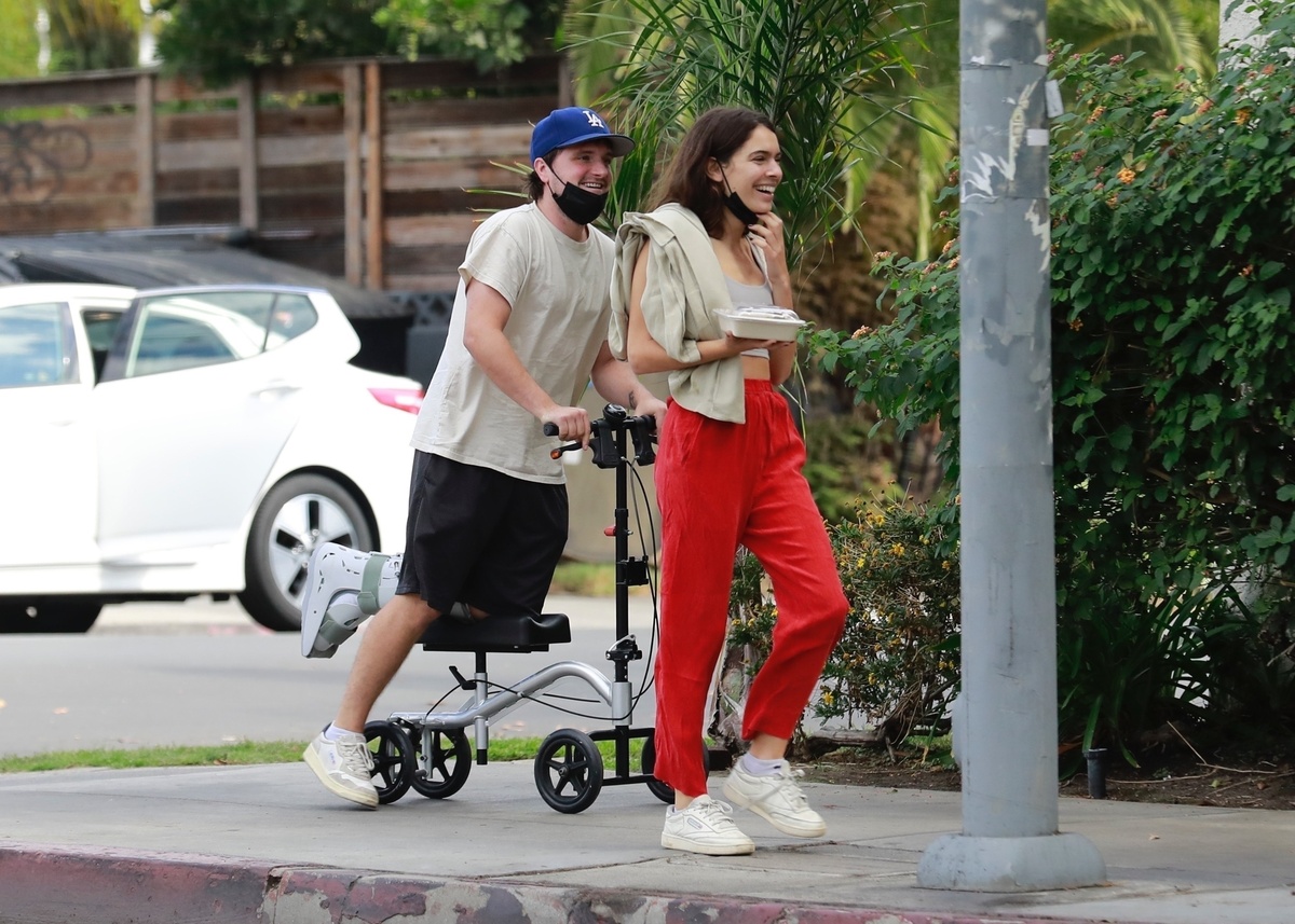 Josh Hutcherson va montado en un aparato mitad scooter mitad muleta, con Claudia Traisac junto a él