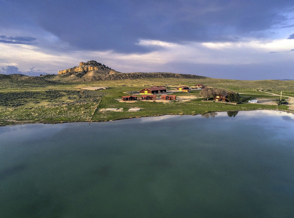 Panorámica del rancho con una colina al fondo y el lago en primer plano