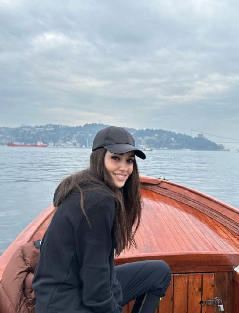 Hande Erçel en una barquita de pesca mirando a cámara sonriente