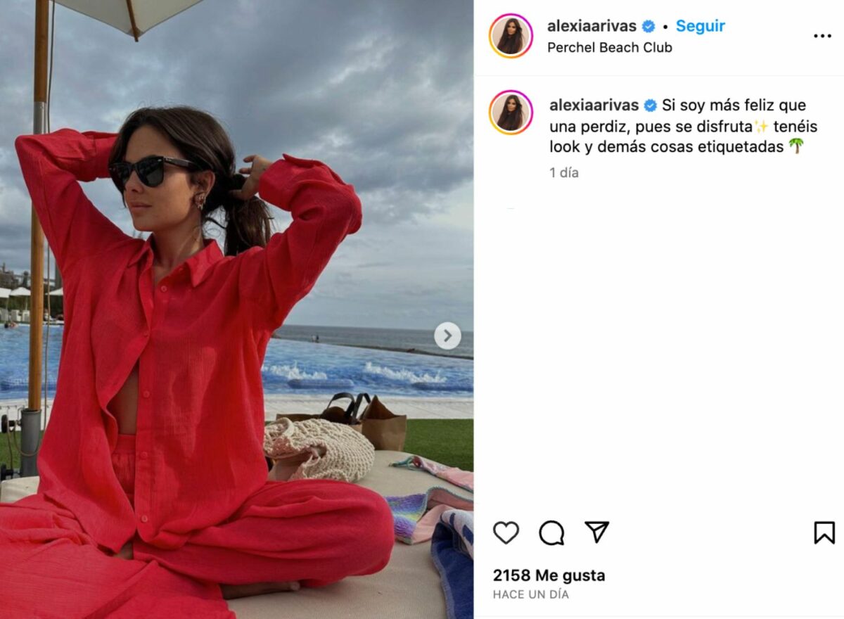 Post de Instagram de Alexia Rivas en el que se la ve sentada junto al mar con un conjunto de lino rojo
